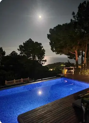 a large swimming pool at night with a full moon at El Desmai in San Pol de Mar