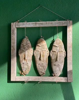 two ancient masks hanging on a green wall at El Desmai in San Pol de Mar