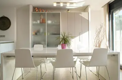 a dining room with a table and white chairs at El Desmai in San Pol de Mar