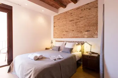 a bedroom with a large bed with a brick wall at Aspasios Charming Flats in Barcelona