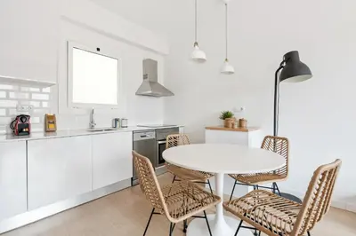 a white kitchen with a white table and chairs at Flateli Calàbria in Barcelona