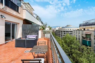 a balcony with a wooden table and chairs on a building at Flateli Calàbria in Barcelona