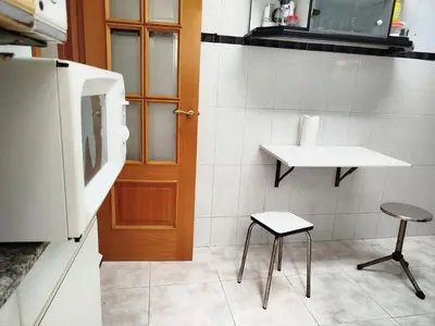 a kitchen with a table and a chair and a refrigerator at La Habitación de Santa Eulalia habitación privada in Hospitalet de Llobregat