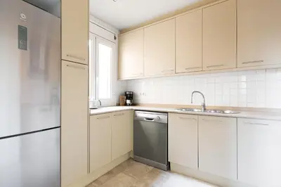a kitchen with white cabinets and a sink and a dishwasher at OLA LIVING - MT - Aire 1 in Barcelona