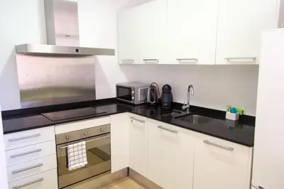 a kitchen with white cabinets and a black counter top at Housalia Ondina Suites Sagrada Familia in Barcelona