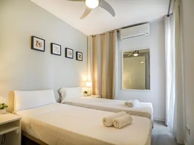 two beds in a room with white walls at Warm Sands Apartment by Hello Homes Sitges in Sitges