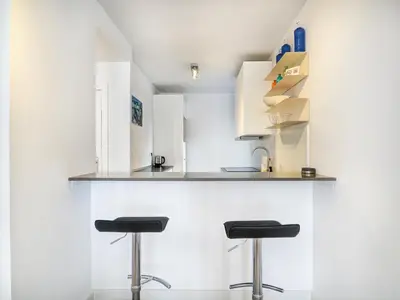 a kitchen with two stools at a counter at Warm Sands Apartment by Hello Homes Sitges in Sitges