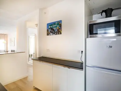 a kitchen with a refrigerator and a microwave at Warm Sands Apartment by Hello Homes Sitges in Sitges