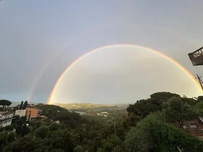 a rainbow in the sky over a city at Vila Viva Mundo in San Cipriano de Vallalta