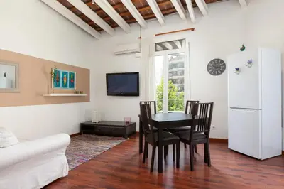 a living room with a table and chairs and a white refrigerator at Urgell in Barcelona