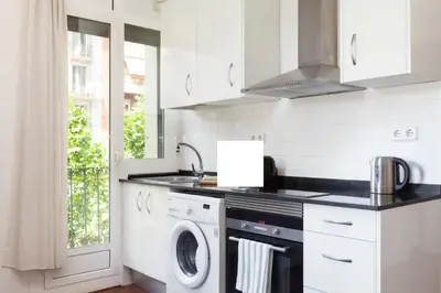 a white kitchen with a washer and dryer at Urgell in Barcelona