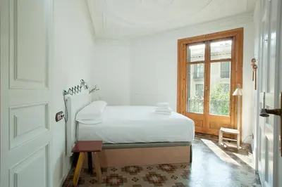 a white bedroom with a bed and a window at yök Casa Cultura in Barcelona