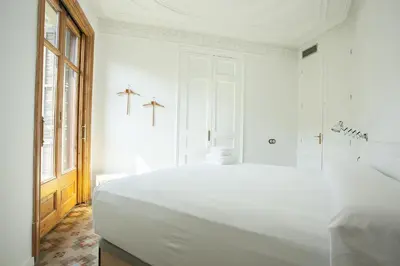 a white bedroom with a large bed and a window at yök Casa Cultura in Barcelona