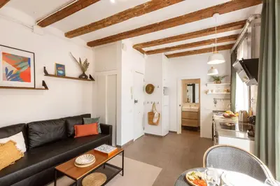 a living room with a black couch and a table at Lodging Apartments Almirall Beach 42 in Barcelona