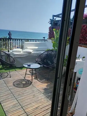 a patio with a couch and chairs and the ocean at Frente al mar con Terraza - Sitges in Sitges