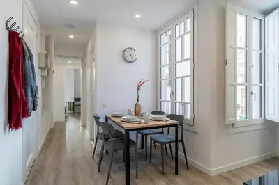 a dining room with a table and chairs and a clock at 4182 - AB Poble Sec - Plaza España X in Barcelona