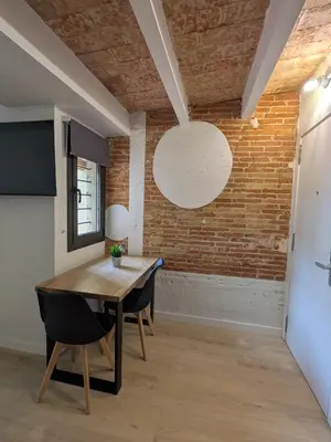 a dining room with a wooden table and a brick wall at Barcelona Touch Apartments - Font Honrada in Barcelona