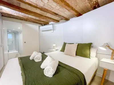 a bedroom with a large white bed with green accents at Barcelona Touch Apartments - Creu dels Molers in Barcelona
