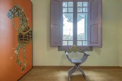 a chair in a room with a painting of a horse on the wall at Can cruspinera WITH 6BEEDROOM in Tiana
