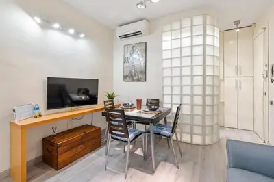 a dining room with a table and chairs and a tv at Steps to Sagrada Família AC Elevator in Barcelona