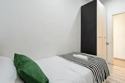 a bedroom with a white bed with a green pillow at Steps to Sagrada Família AC Elevator in Barcelona