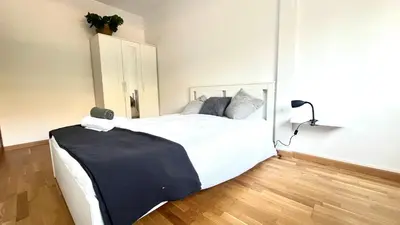 a bedroom with a large bed with white sheets and gray pillows at Apartamento independiente con jardín in Terrassa