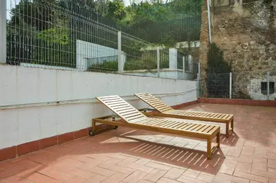 two lounge chairs sitting on a patio next to a fence at Park Guell in Barcelona