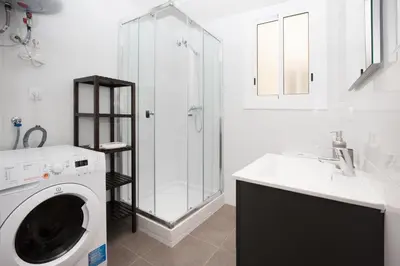 a white bathroom with a washing machine and a sink at Park Guell in Barcelona
