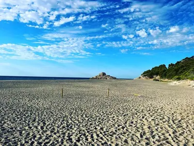 a sandy beach with a rocky island in the distance at Ibiza style villa with swimming pool near Sitges in Cunit