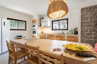 a kitchen and dining room with a wooden table and chairs at Ibiza style villa with swimming pool near Sitges in Cunit
