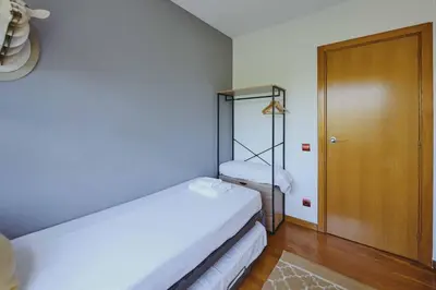 a small room with two beds and a wooden door at 3 bedroom Huge apartament near the beach in Sant Adria de Besos