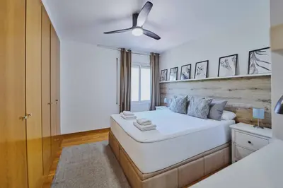 a bedroom with a large white bed and a ceiling fan at 3 bedroom Huge apartament near the beach in Sant Adria de Besos