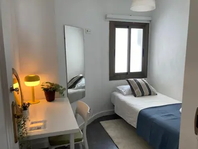 a small room with a bed and a table and a window at Toledo House Self Checkin in Hospitalet de Llobregat