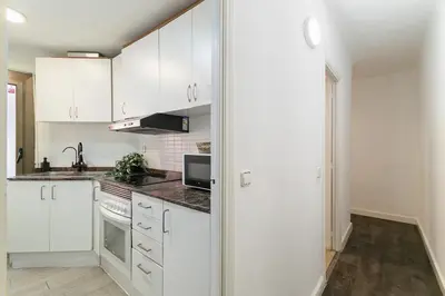 a white kitchen with white cabinets and a sink at Toledo House Self Checkin in Hospitalet de Llobregat