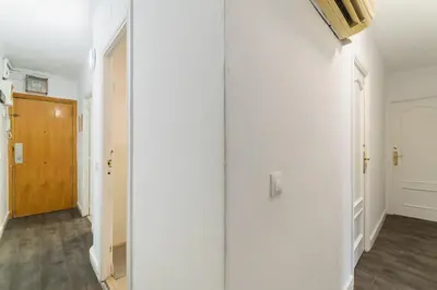 a hallway with white walls and a wooden door at Toledo House Self Checkin in Hospitalet de Llobregat