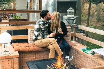 a man and a woman kissing next to a fire at Caravana Airstream Vintage del 67 en Orrius, Barcelona in Orrius