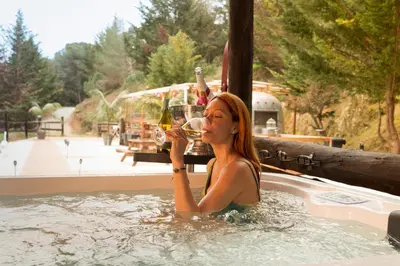a woman in a hot tub with a glass of wine at Caravana Airstream Vintage del 67 en Orrius, Barcelona in Orrius