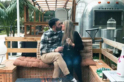 a man and a woman kissing on a bench at Caravana Airstream Vintage del 67 en Orrius, Barcelona in Orrius