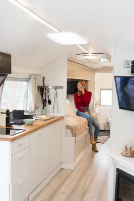 a woman sitting on a bed in a camper at Caravana Airstream Vintage del 67 en Orrius, Barcelona in Orrius