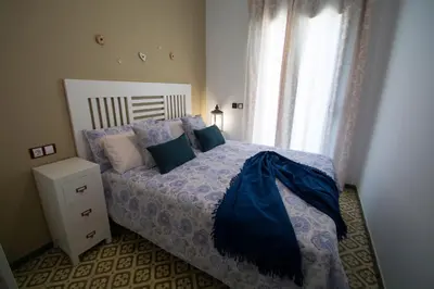 a bedroom with a bed with blue sheets and a window at Casa grande con piscina en el centro de Calella, Tramuntana in Calella