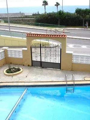 a swimming pool with a gate in front of a building at Apartamento Pineda de Mar con Vistas al Mar in Pineda de Mar