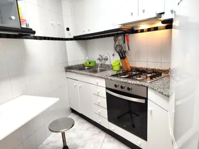 a white kitchen with a stove and a sink at La habitación de Santa Eulalia in Hospitalet de Llobregat