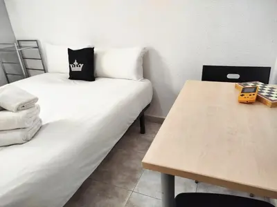 a room with two beds and a wooden table at La habitación de Santa Eulalia in Hospitalet de Llobregat