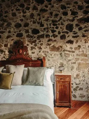 a bedroom with a bed and a stone wall at Paratgea in Llinars del Vallès
