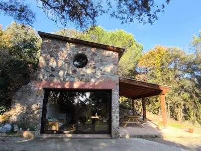 a small stone building with a large window at La Coma in gualba de Dalt