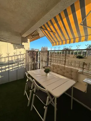 a table and chairs under an umbrella on a balcony at Apartamento con Terraza,Piscina,Playa y Aire acondicionado in Pineda de Mar