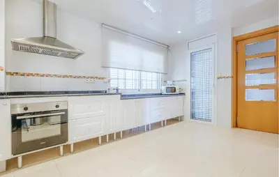 a kitchen with white cabinets and a stove top oven at Lovely Home In Segur De Calafell in Segur de Calafell