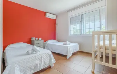 two beds in a room with a red wall at Lovely Home In Segur De Calafell in Segur de Calafell