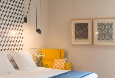 a bedroom with a bed and a yellow chair at The Conica Deluxe Bed&Breakfast in Barcelona