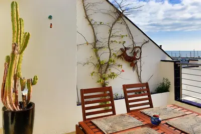 a table with two chairs and a cactus on a balcony at Stunning sea views over marina with swimming pool in Sitges